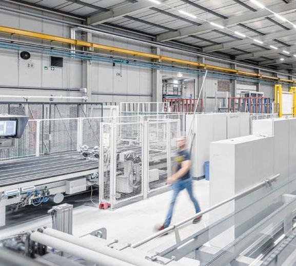 A roll-forming line in a production hall, steel strip running through the stands with an operator alongside.